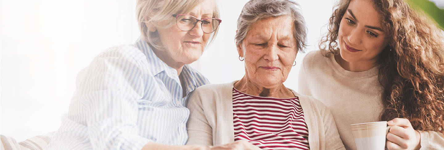 Senior surrounded by loved ones looking at computer tablet
